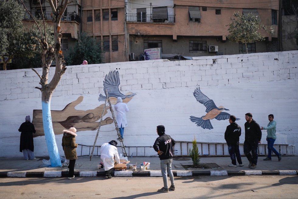 Dei volontari disegnano un murales con i simboli della pace a Damasco, il 12 gennaio 2025 