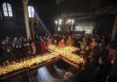 Fedeli e sacerdoti in una chiesa attorno a una tavolata a forma di croce coperta di vasetti di miele e candele accese