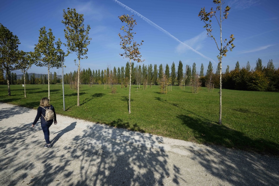 Una donna con uno zaino in spalla attraversa un sentiero lungo il parco