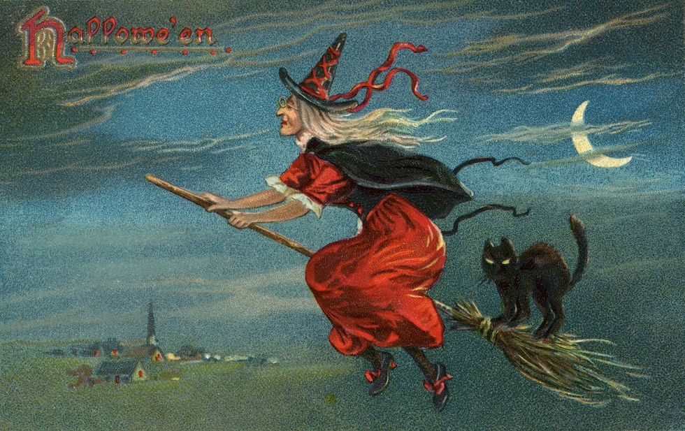 Un’illustrazione d’epoca che mostra una strega e un gatto nero su una scopa, che sorvolano un paese di notte