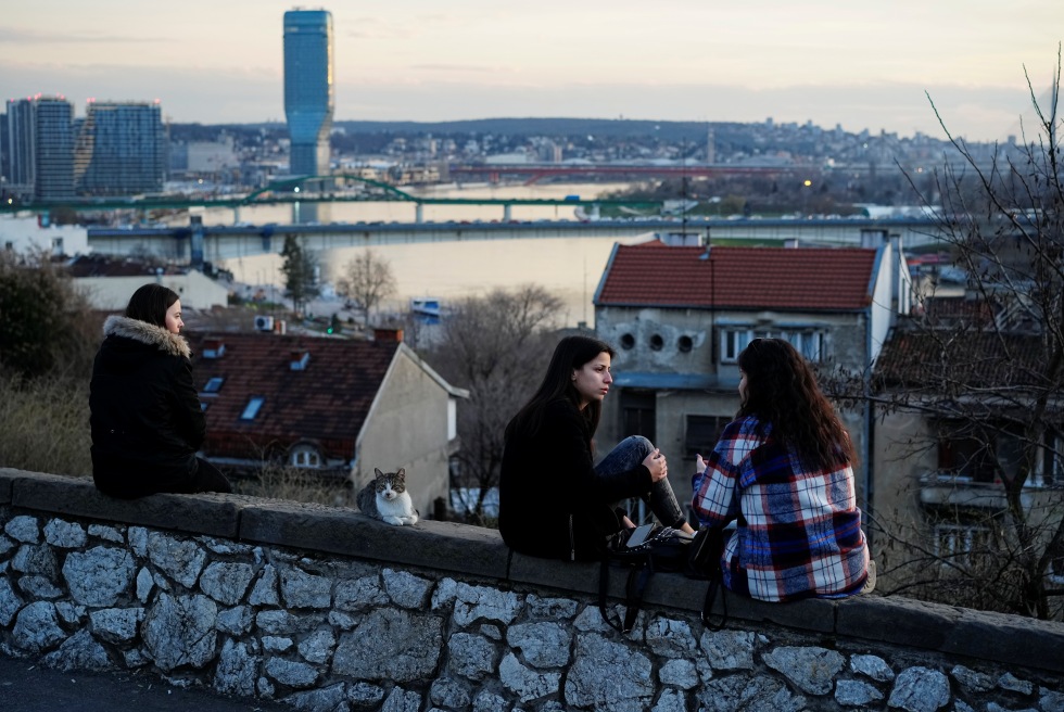 Alcune persone sedute su un muretto nel centro di Belgrado (AP/Pavel Golovkin)
