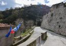 La strada di accesso al paese, con un edificio che mostra la bandiera europea, quella greca e quella italiana