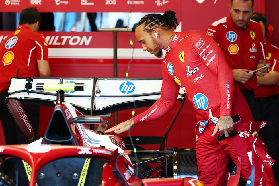 Hamilton accenna un sorriso mentre posa una mano sulla macchina