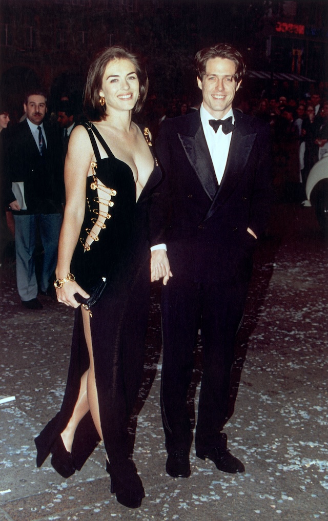 Una foto di Elizabeth Hurley mentre indossa il famoso "safety pin dress" di Versace, insieme all'allora fidanzato Hugh Grant alla prima di <em>Quattro matrimoni e un funerale</em>, Londra, 11 maggio 1994