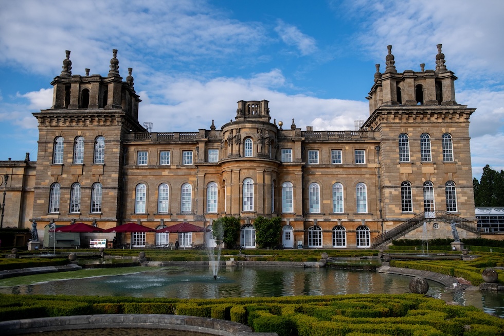 la facciata di una reggia inglese, con davanti un giradino con uno stagno 