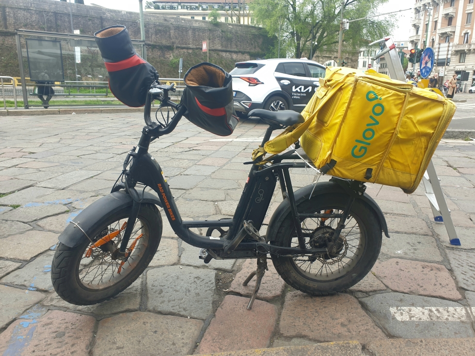 La bicicletta a pedalata assistita di un rider, con i guanti montati sul manubrio (Il Post)