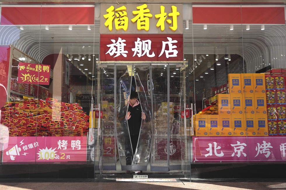 Un uomo esce da un negozio a Pechino, gennaio 2025
