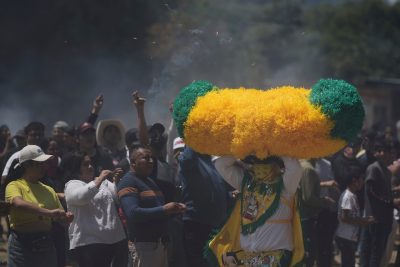 Una persona, chiamata "sayon", corre con un cappello di carta velina mentre gli spettatori lanciano fiammiferi accesi su di lei durante le celebrazioni pasquali.
