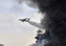 Un aereo dei vigili del fuoco lascia cadere dell'acqua sul grande incendio nel porto