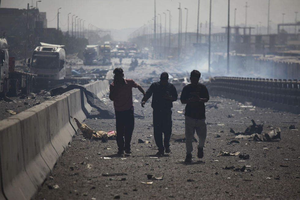 Uomini camminano tra le macerie a Bandar Abbas, 26 aprile 2025 