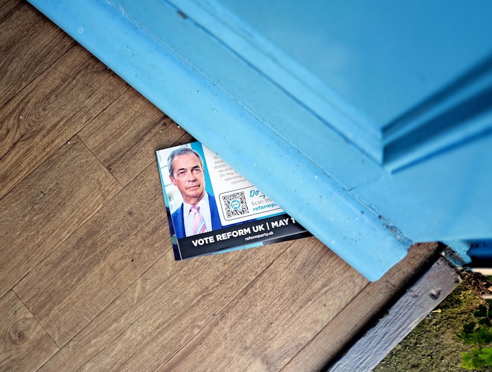 Un volantino di Reform UK sbuca da sotto una porta, il 27 aprile 