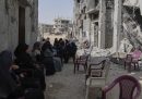 Donne palestinesi sedute tra le macerie e i palazzi distrutti dall'esercito israeliano