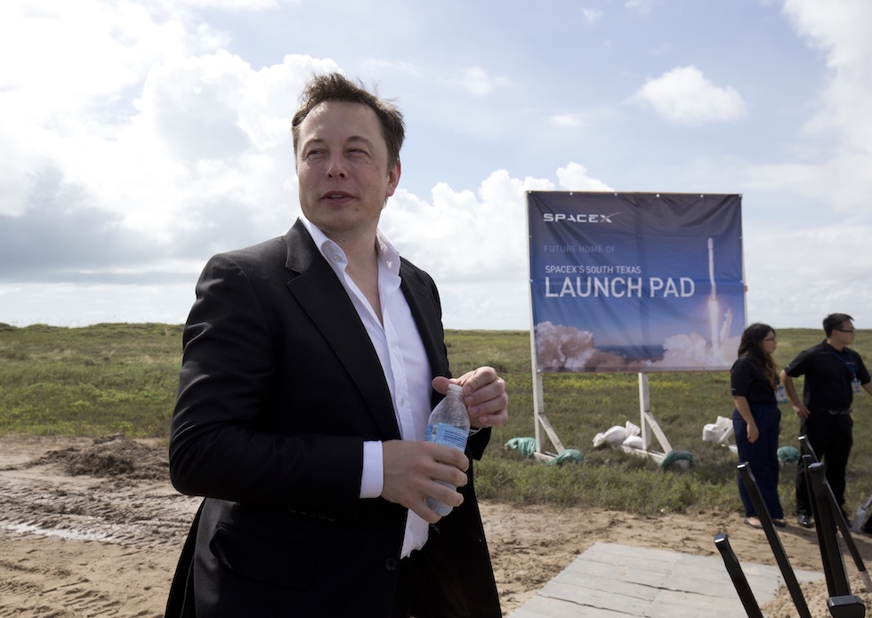 Elon Musk avvita una bottiglietta d'acqua durante una conferenza all'aperto