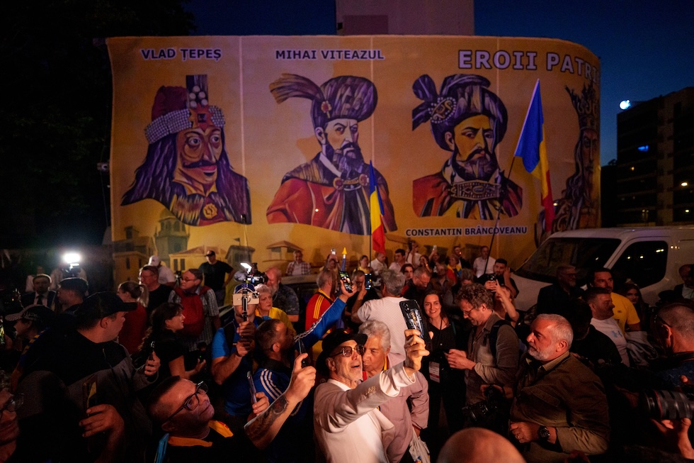 Sostenitori di Simion festeggiano alla diffusione degli exit poll, il 4 maggio. Sullo sfondo, nella sede di Aur, ci sono alcune figure storiche romene tra cui Vlad l'impalatore 
