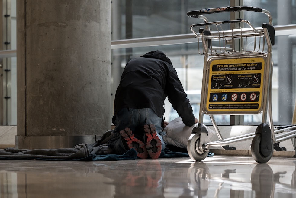 Una persona allestisce un letto di fortuna dentro il terminal 4 dell'aeroporto di Madrid, il 12 maggio