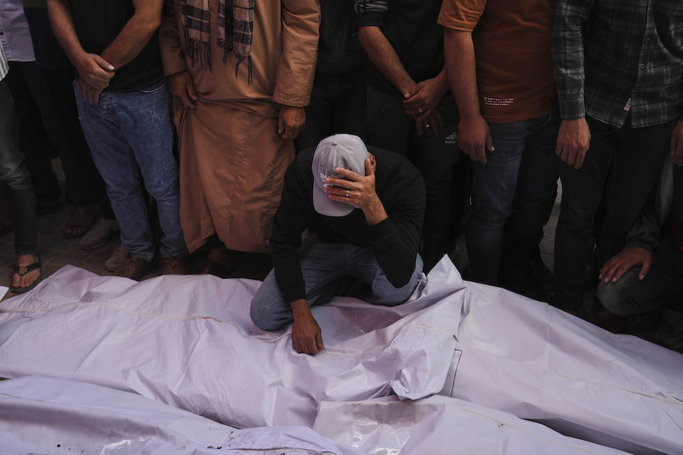 Un uomo davanti ad alcuni cadaveri all'obitorio dell'ospedale al Aqsa di Gaza, il 20 maggio 2025