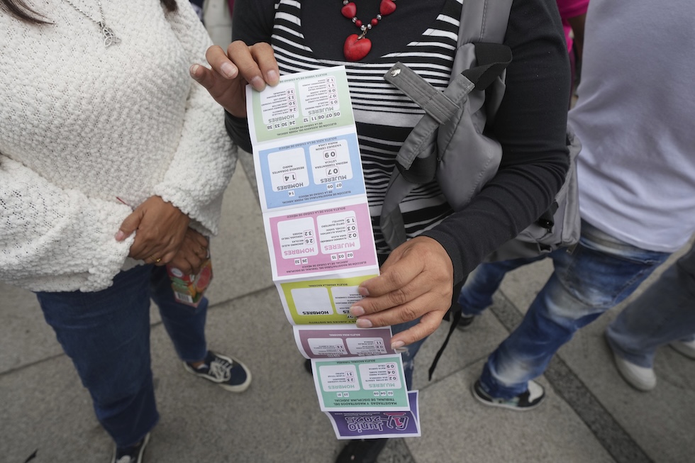 Un'elettrice mostra le istruzioni di voto ricevute da una candidata, con il fac-simile delle schede 