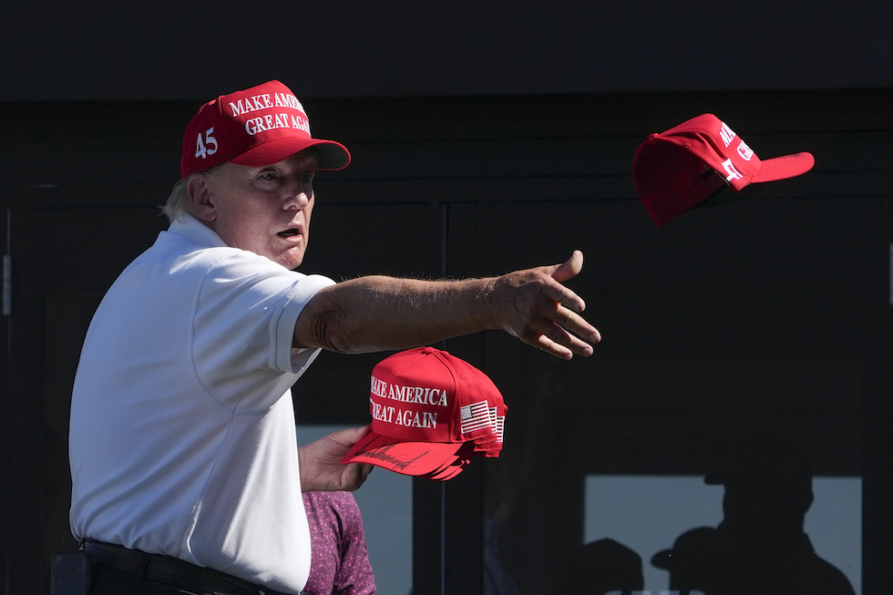 Donald Trump lancia cappellini "Make America Great Again" (MAGA) nell'agosto 2023 (AP Photo/Seth Wenig, File)