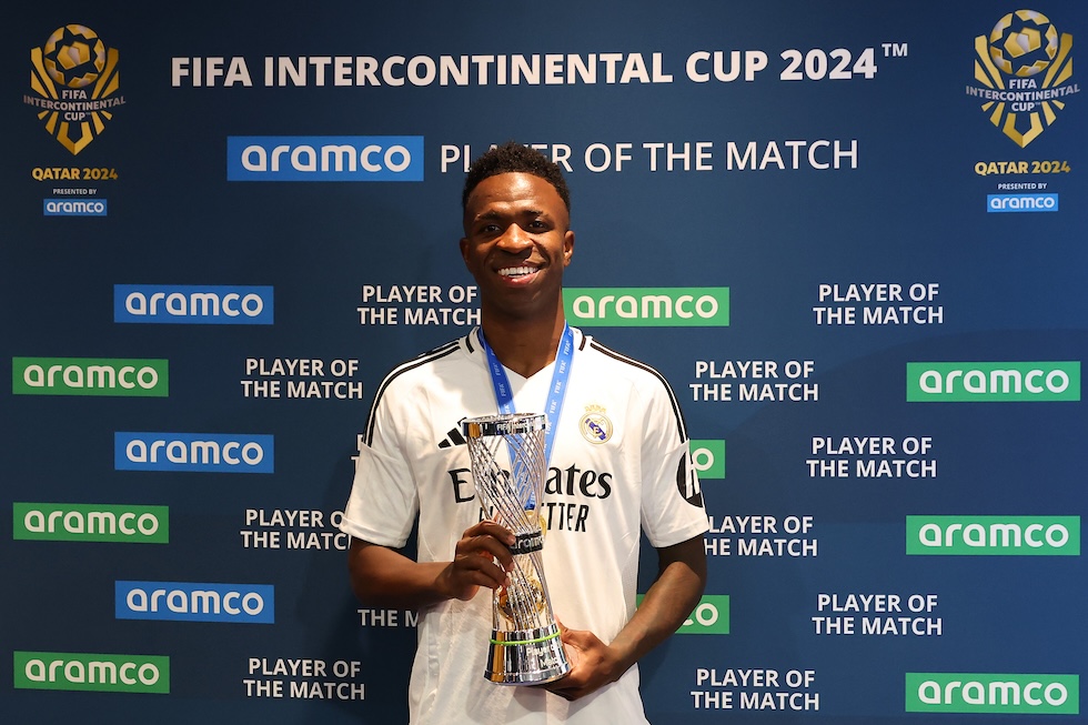 Il calciatore brasiliano del Real Madrid Vinicius Junior riceve il premio di miglior giocatore per la Coppa Intercontinentale FIFA con dietro il logo di Aramco ripetuto più volte, 18 dicembre 2024 (Christopher Pike - FIFA/FIFA via Getty Images)