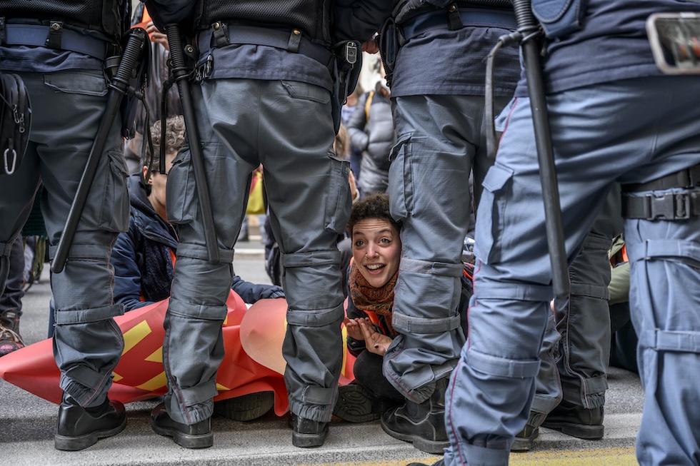 Un'attivista di Ultima Generazione durante un'azione organizzata a Milano nel 2023, circondata da poliziotti