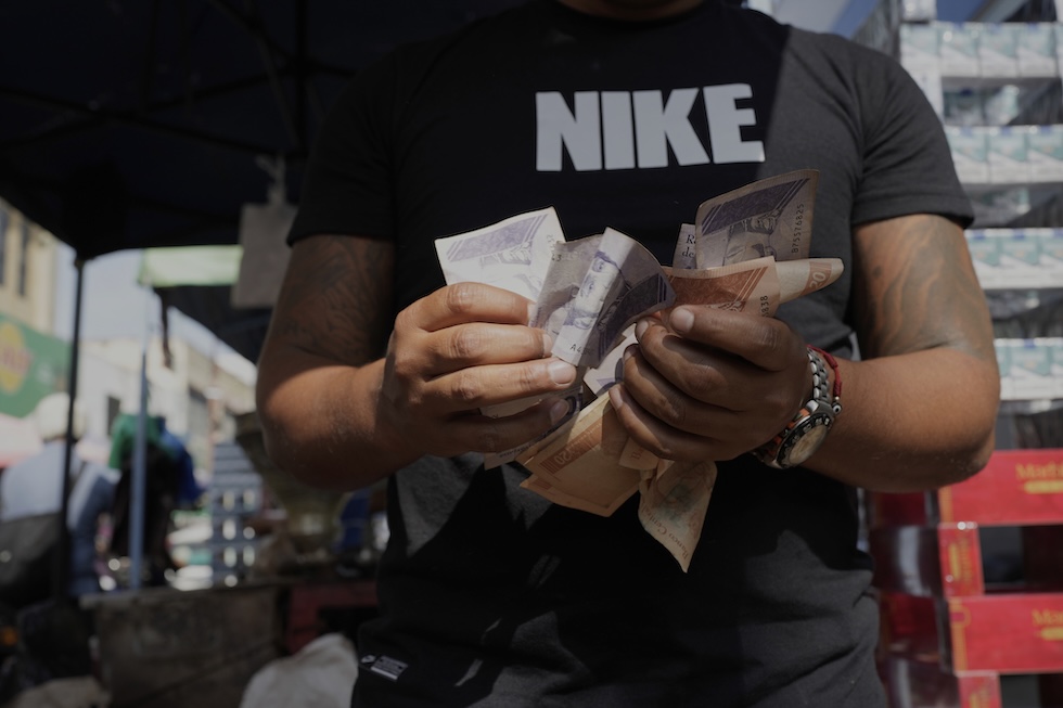 Un uomo conta una mazzetta di bolívar, la valuta venezuelana