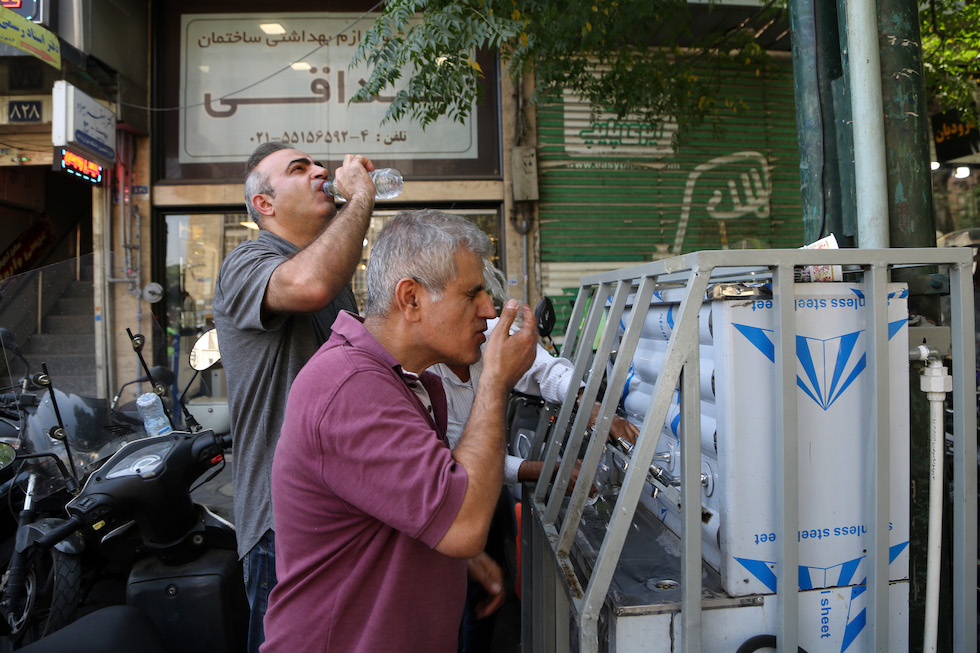 Alcuni uomini bevono acqua da un distributore pubblico a Teheran, 22 luglio 2025 