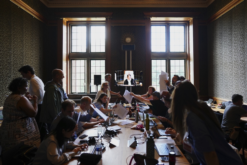 Un gruppo di giornalisti si passa il testo del parere consultivo durante il discorso del giudice Yuji Iwasawa, 23 luglio 2025