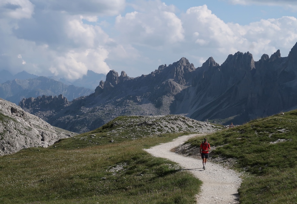 Un uomo percorre un sentiero, con le montagne sullo sfondo