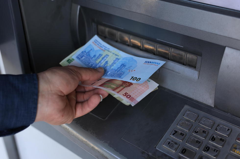 Un uomo ritira denaro da uno sportello automatico in Iran, 4 agosto 2025