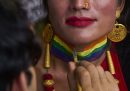 Una persona si fa dipingere sul collo la bandiera arcobaleno in occasione della parata del Pride.