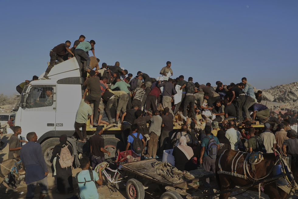 Persone palestinesi assaltano un camion appena entrato a Gaza, 4 agosto 2025