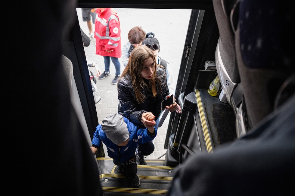 Una donna insieme al figlio sale su un bus diretto a Varsavia, la capitale della Polonia, dalla città ucraina di Leopoli, nel maggio 2022