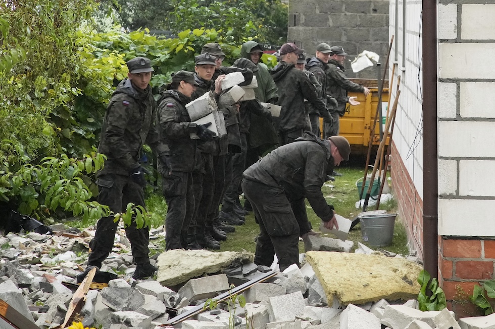 Una squadra della difesa territoriale polacca rimuove i detriti di un tetto crollato per l'impatto di uno dei droni, a Wyryki in Polonia, l'11 settembre 
