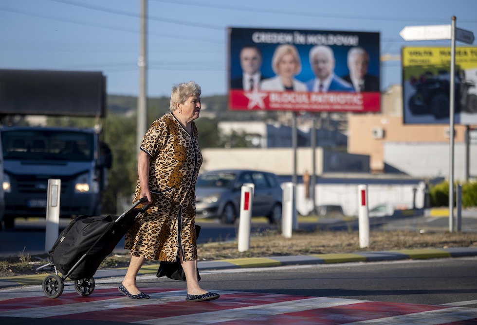 Una donna cammina davanti a un cartellone elettorale della coalizione dell'ex presidente Dodon, a Hîncești, il 4 settembre 