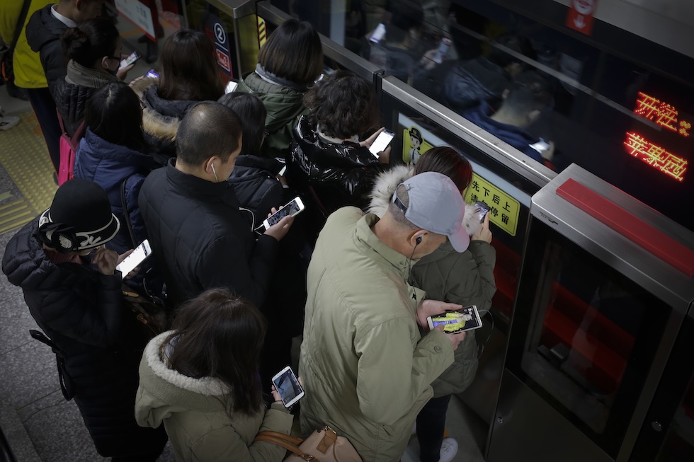 Un gruppo di pendolari concentrati sui loro smartphone prima di salire su un vagone della metropolitana