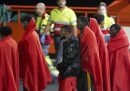 Persone migranti arrivano al porto di Arrecife avvolti in delle coperte rosse, dopo essere stati soccorsi dalle autorità spagnole
