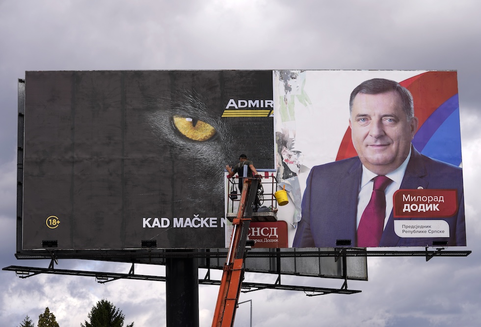 Un uomo rimuove un manifesto elettorale con la fotografia di Milorad Dodik dopo le elezioni del 2022 a Banja Luka, in Bosnia Erzegovina