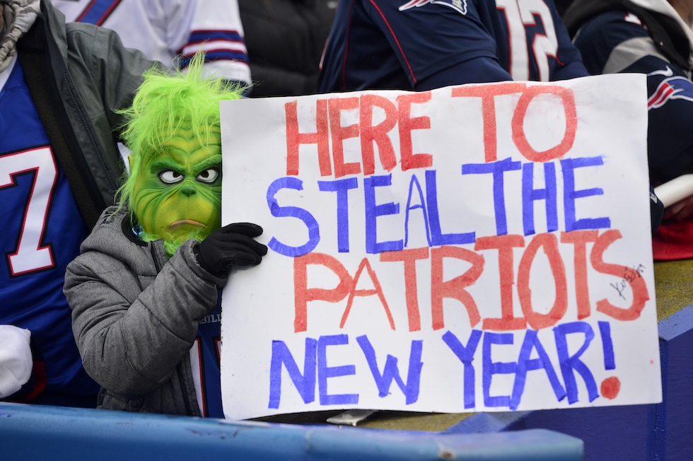 Un tifoso dei Buffalo Bills mascherato da Grinch durante una partita contro i Patriots. Sul cartello c'è scritto "Qui per rubare il Capodanno ai Patriots", 31 dicembre 2023 (AP Photo/Adrian Kraus)