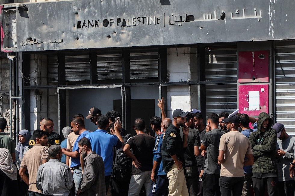 Persone in coda fuori da uno dei pochi sportelli bancari di Gaza che ha riaperto, nella città di Gaza, il 23 ottobre