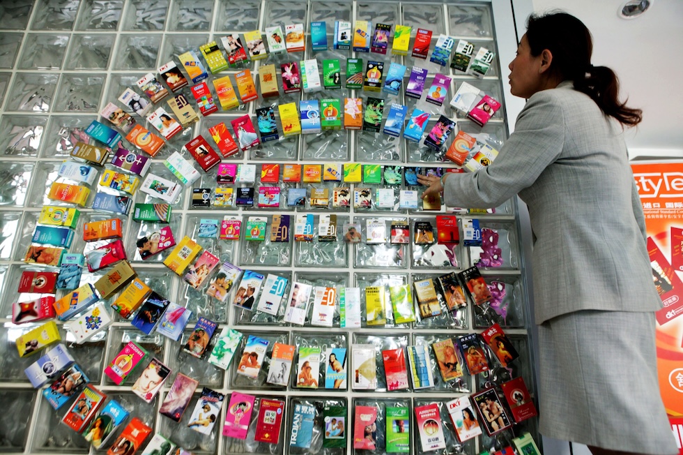 Una donna davanti a diverse confezioni di preservativi a un'esposizione a Shanghai, nel 2005
