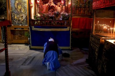 Una donna prega nella Basilica della Natività, costruita sopra la grotta in cui si crede sia nato Gesù, il 24 dicembre a Betlemme