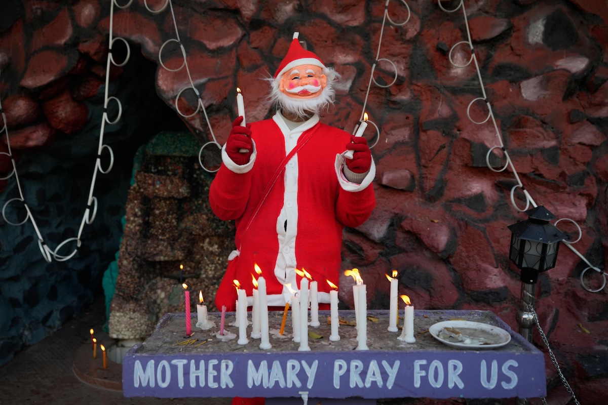 Un ragazzino vestito da Babbo Natale regge alcune candele in mano durante una celebrazione di Natale a Srinagar, nella regione del Kashmir controllata dall'India, 25 dicembre 2025 (AP Photo/Mukhtar Khan)