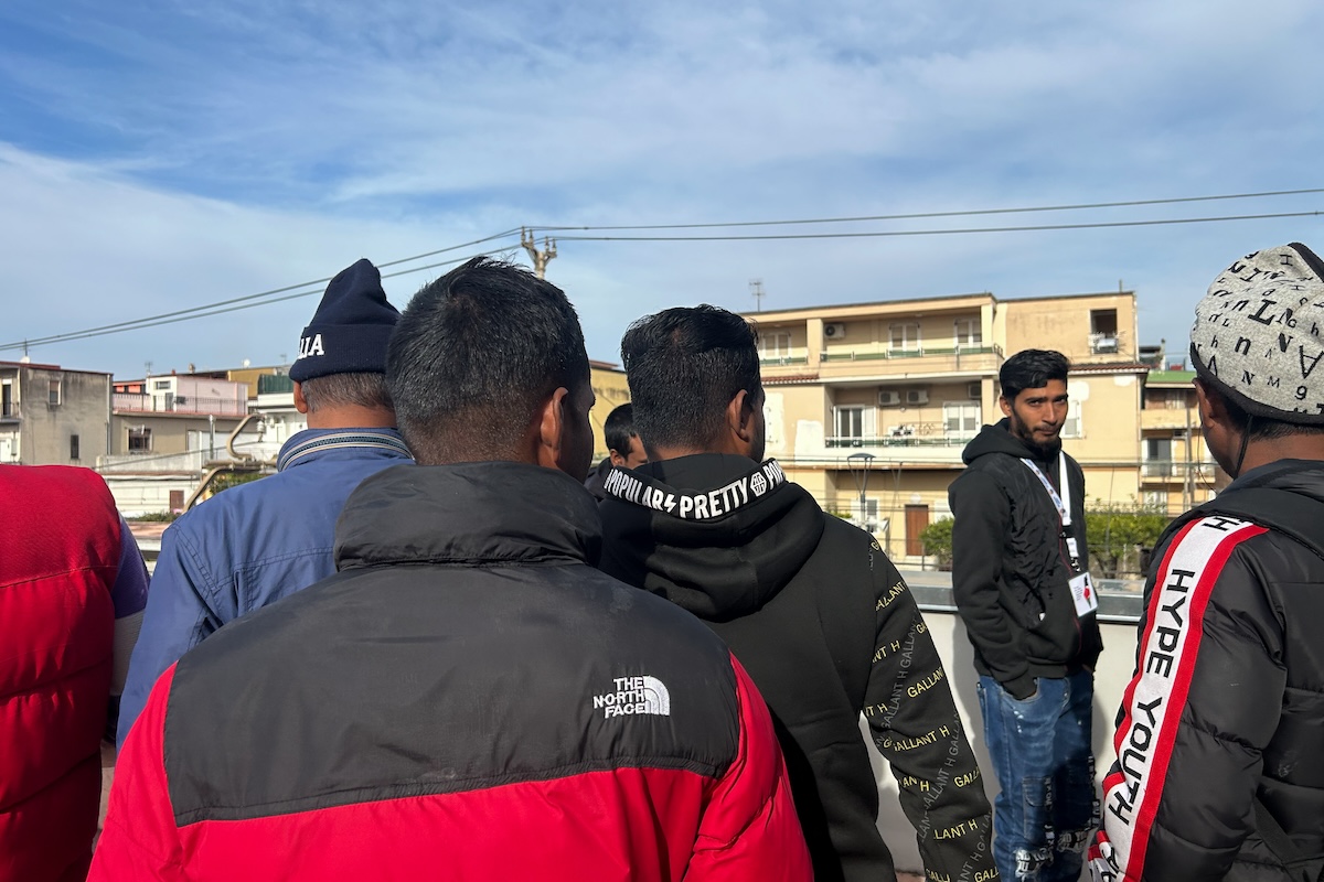 Aziz Nanouche, l'operatore legale della Rete vesuviana solidale che traduce le denunce, con un gruppo di migranti (Angelo Mastrandrea/il Post)