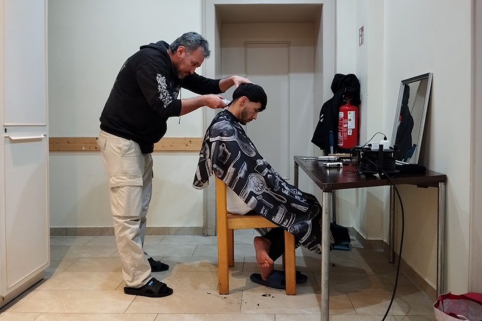 Un richiedente asilo si fa tagliare i capelli all'interno della chiesa luterana della Trinità di Steglitz (Rodolfo Toè/il Post)