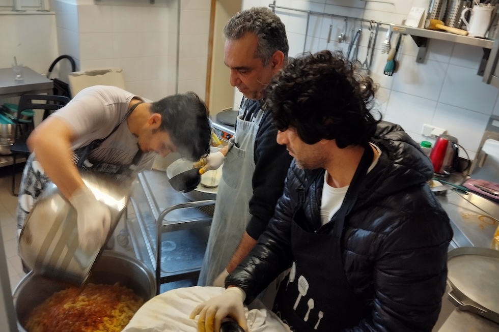 Alcuni richiedenti asilo ospiti della chiesa della Trinità mentre cucinano il pranzo (Rodolfo Toè/il Post)