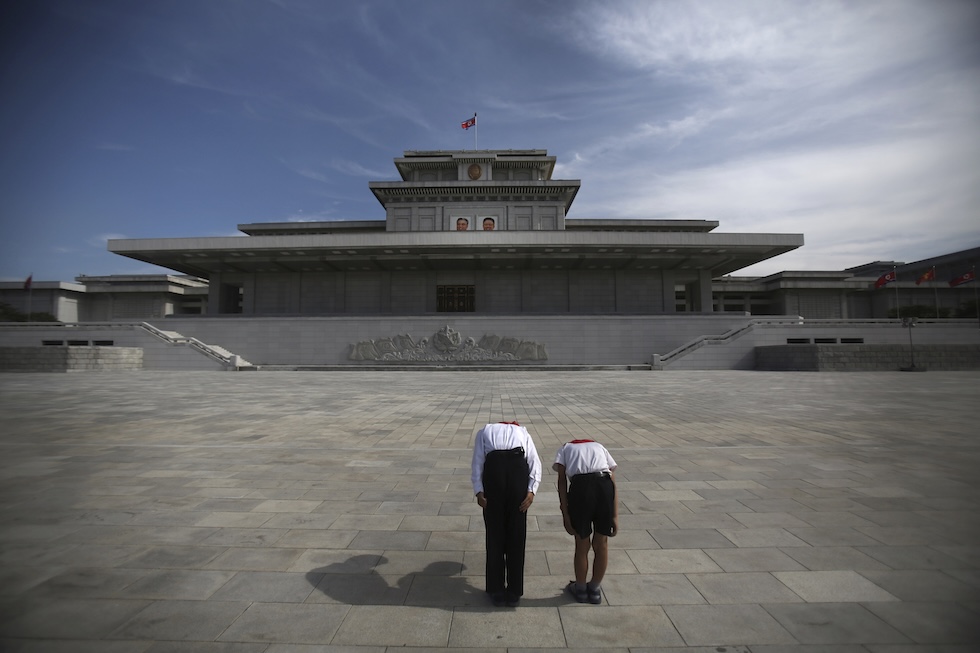 Due studenti nordcoreani si inchinano davanti ai ritratti di Kim Il Sung e Kim Jong Il, appesi all'ingresso del mausoleo di Kumsusan, nel 2013 (AP/Wong Maye-E, File)