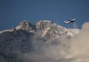 Un aereo in volo, con le cime di una montagna sullo sfondo