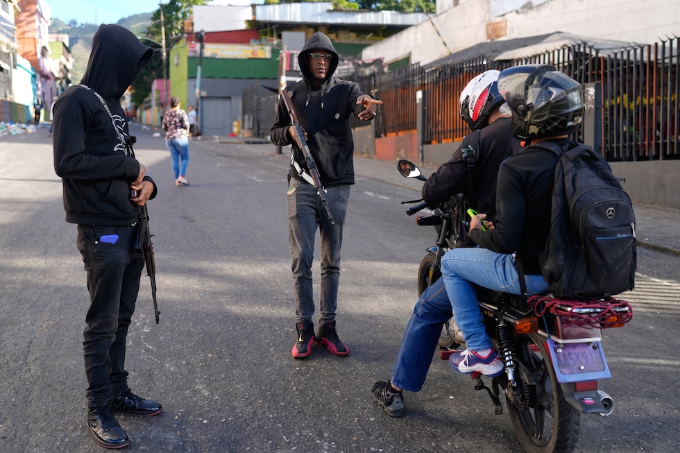 Due civili appartenenti a un colectivo fermano delle persone su uno scooter a Caracas, il 4 gennaio. (AP Photo/Ariana Cubillos)