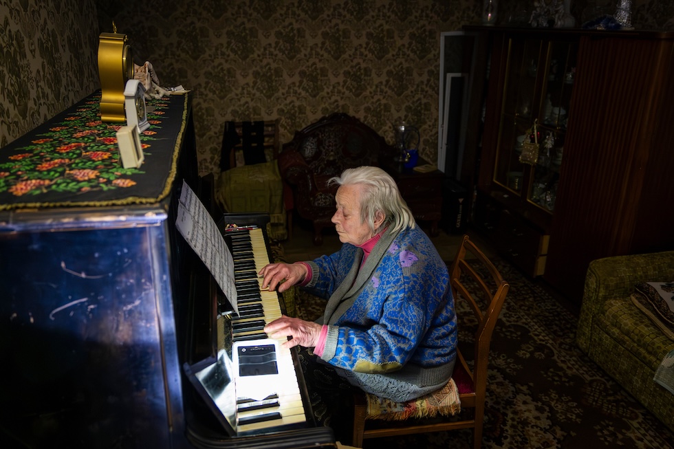 Una donna ucraina, Raisa Derhachova, suona il pianoforte durante un blackout in casa sua a Kyiv, il 13 gennaio 2026 (AP Photo/Dan Bashakov)