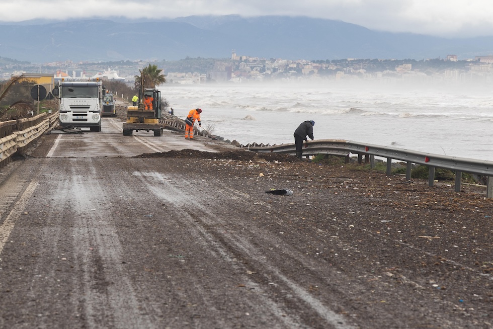 Operai al lavoro per sistemare la strada statale 195, vicino a Cagliari, chiusa al traffico per via dei danni causati dalla mareggiata 